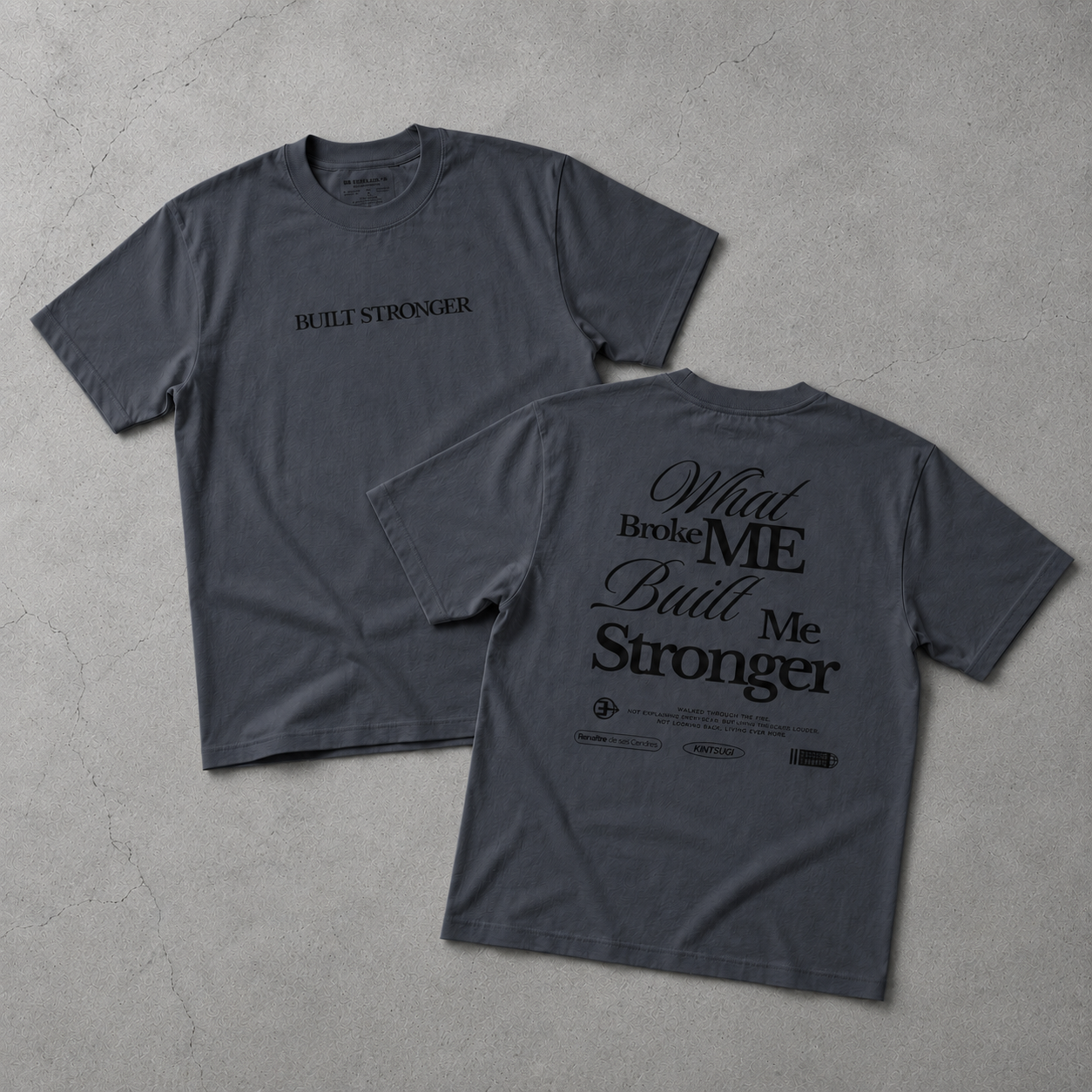 Gray t-shirt with 'Built Stronger' text on a concrete surface