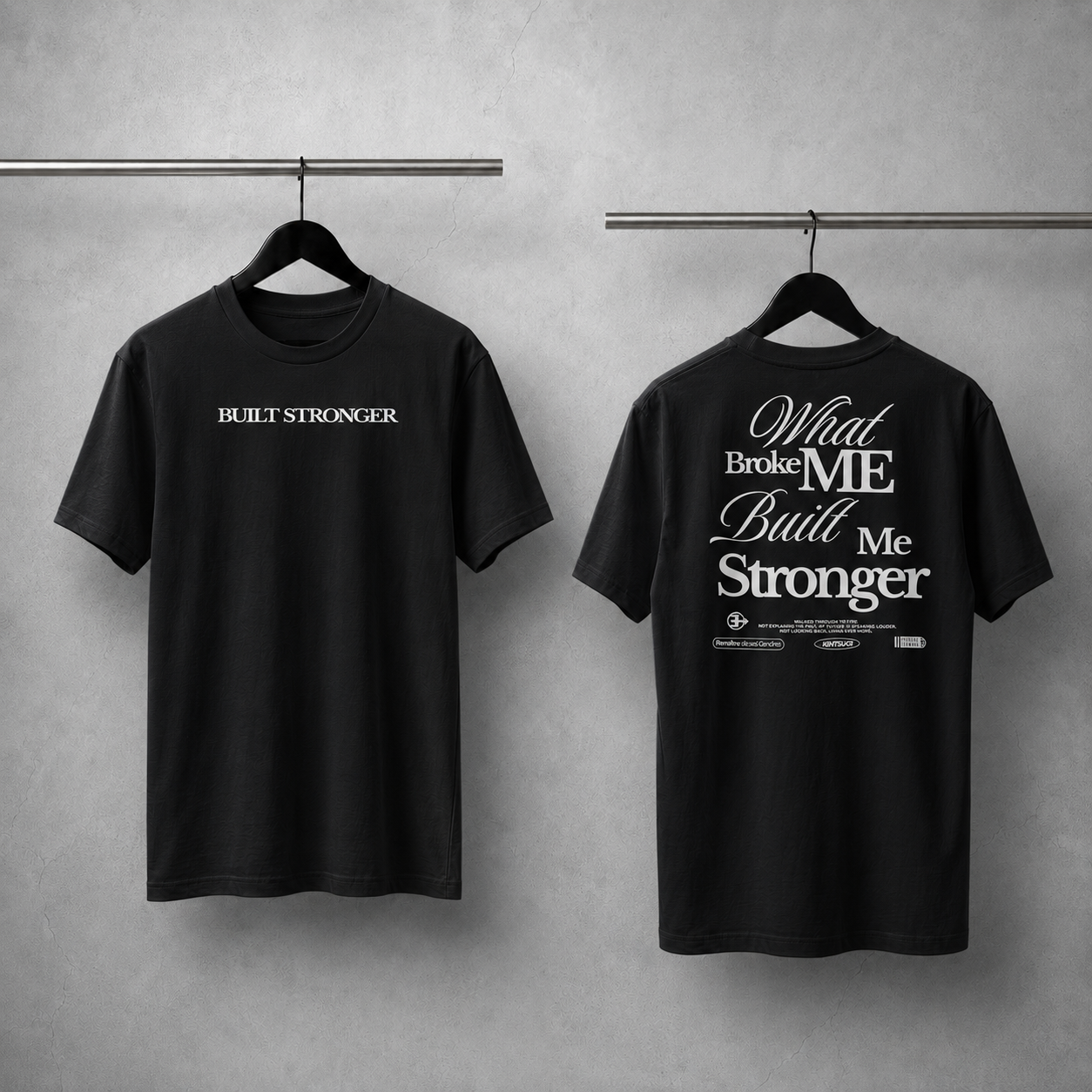 Two black t-shirts with motivational phrases on hangers against a gray background